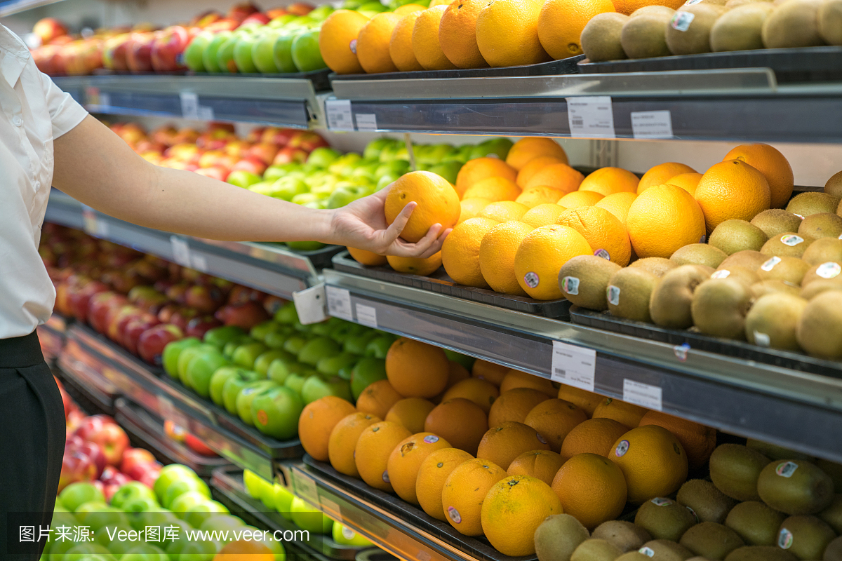 超市货架上的新鲜健康水果。用女人的手挑选最好的水果